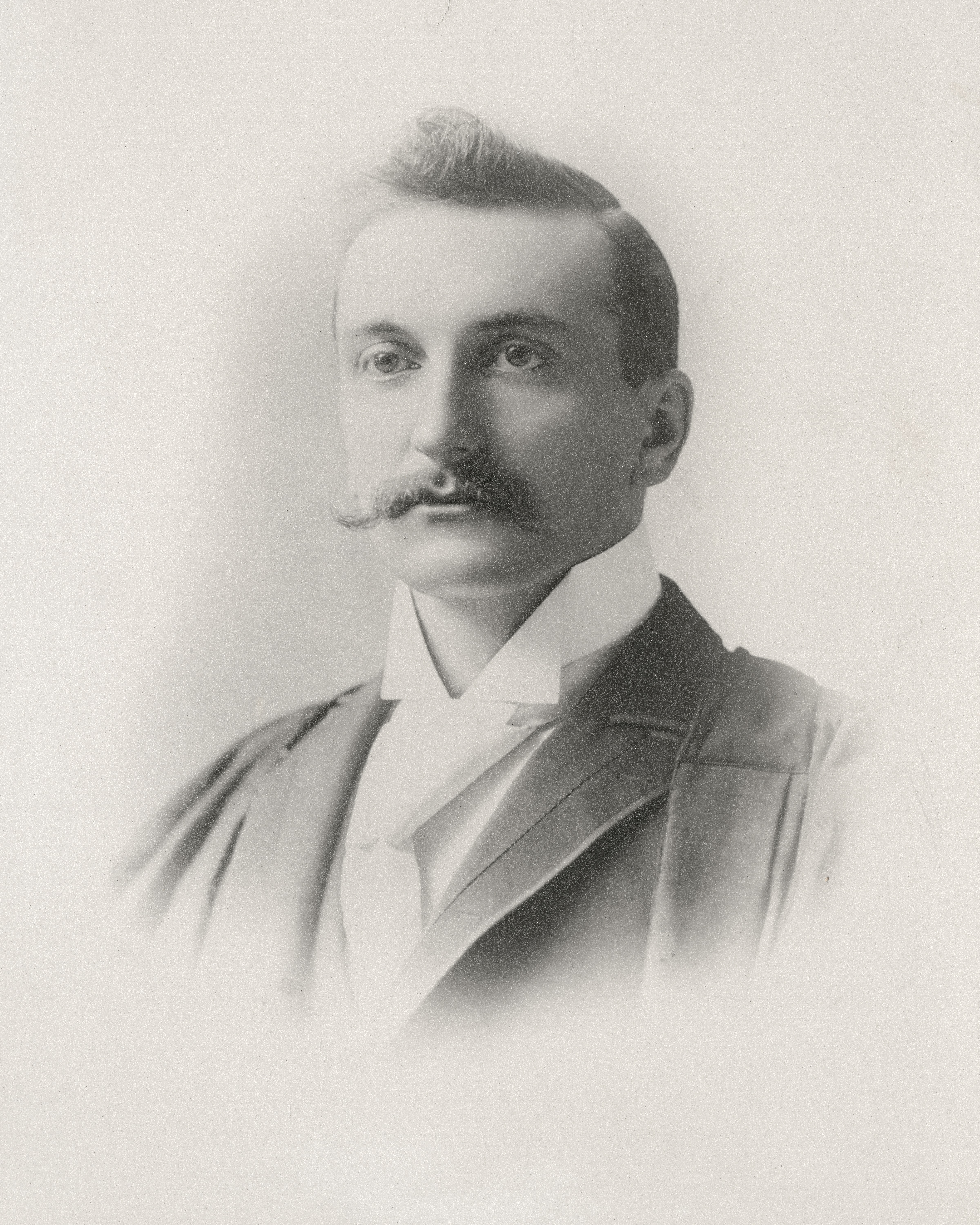 Black and white portrait photo of Dr. MacLaren with a bit of hair standing up at the front and alarge moustache.