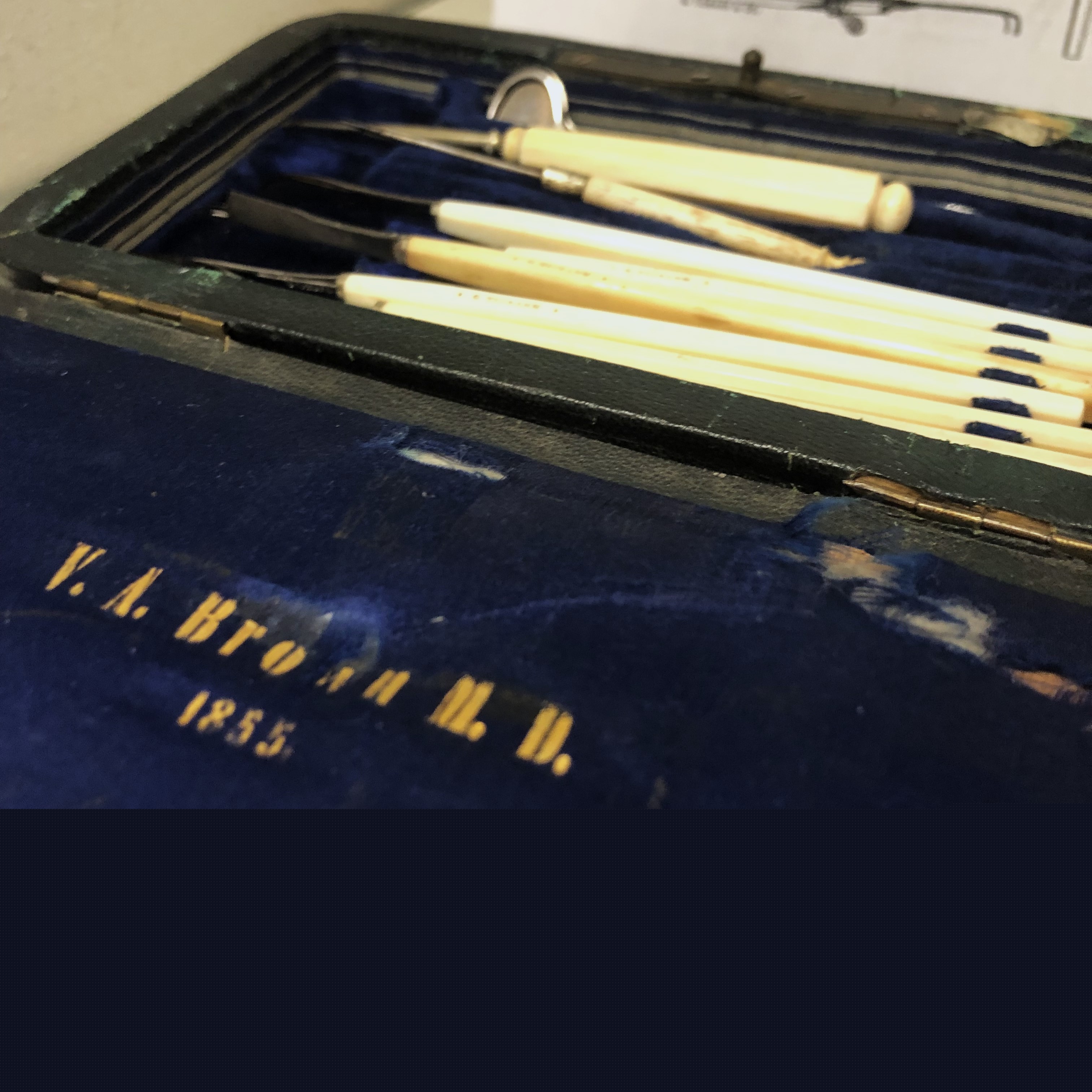 A blue velvet lined case with a set of small medical instruments with yellow handles